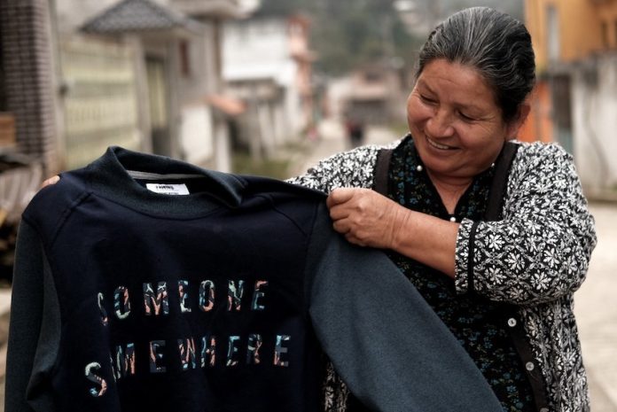 A woman holding a sustainabily made jumper